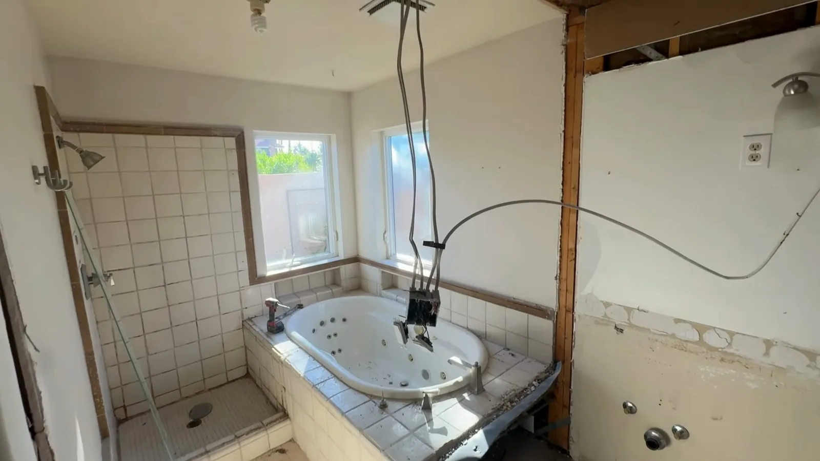 Bathroom stripped back to studs with a whirlpool tub in place and tiled walls partly removed