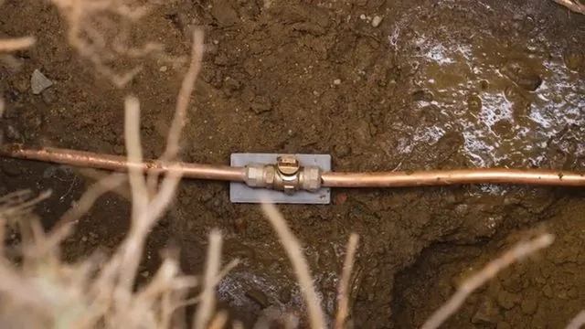 Copper water line with a coupling lying in dirt in a shallow trench