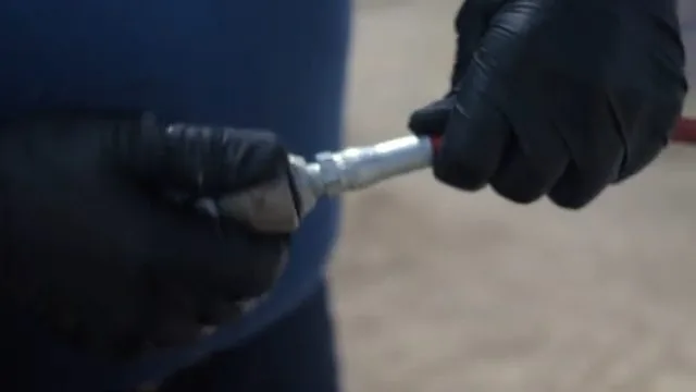 Hand holding a jetting nozzle on a red hose