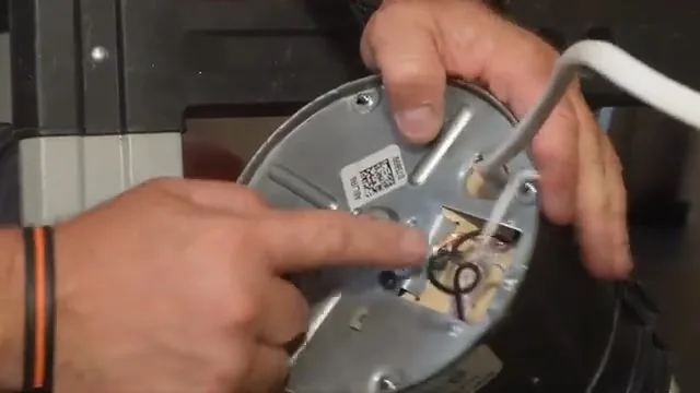 Hands pointing at the metal wiring plate on the underside of a garbage disposal