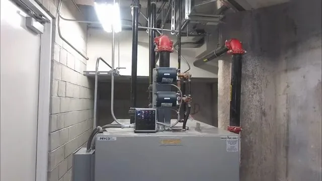 Large commercial water heater with red valves and piping in a concrete-walled mechanical room