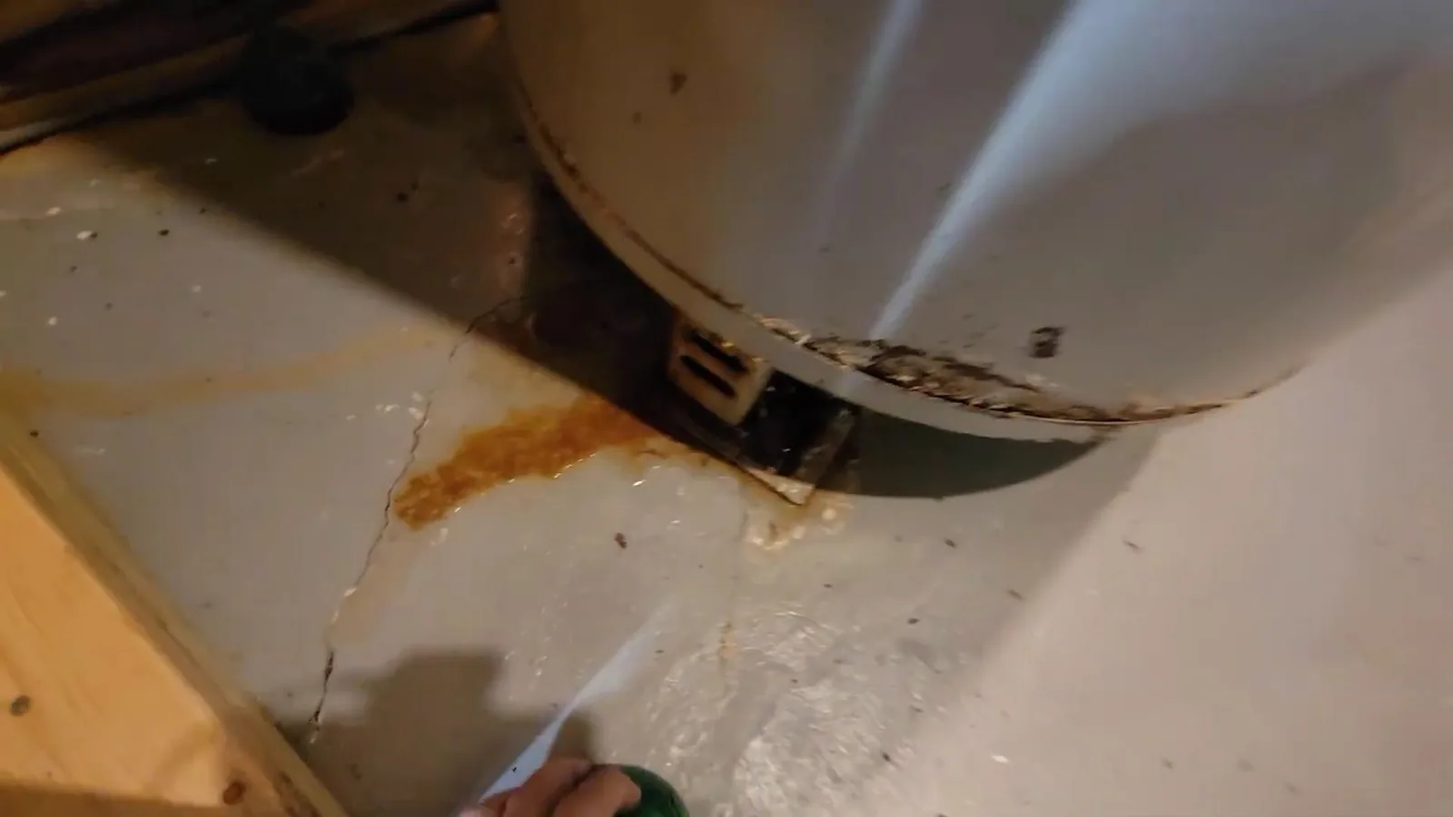 Rust-colored stain on a floor under the base of a water heater tank