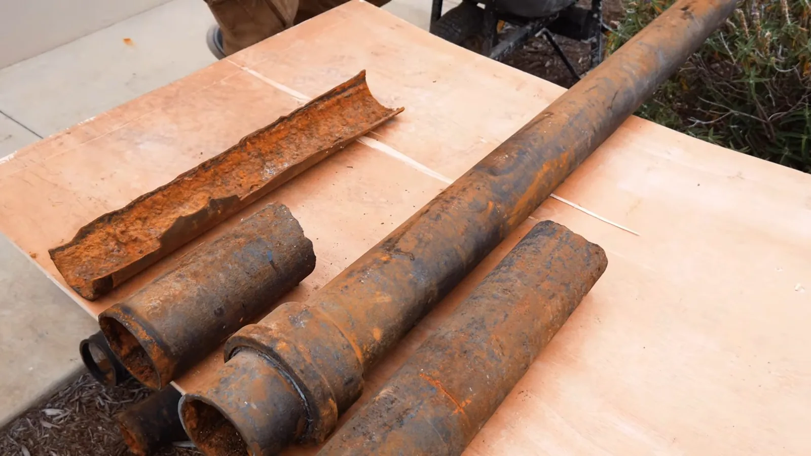 Several rusty cast iron pipe sections, one split lengthwise, lying on a table