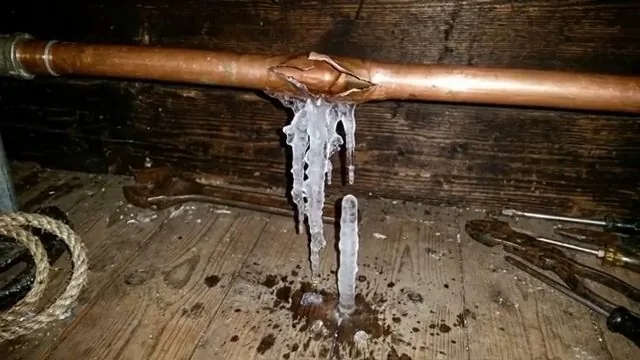 Copper pipe split along the seam with icicles hanging from it