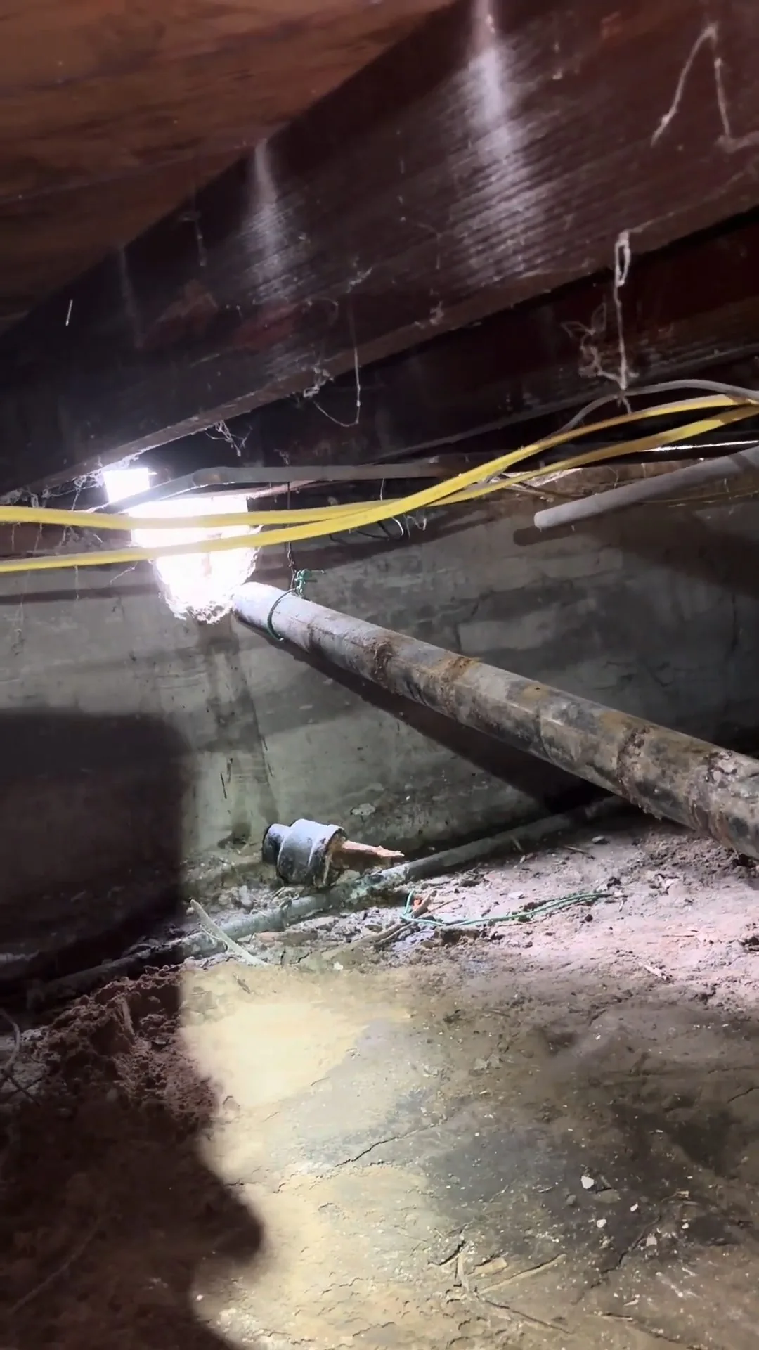 Crawlspace with a pipe along the wall and standing water on the ground