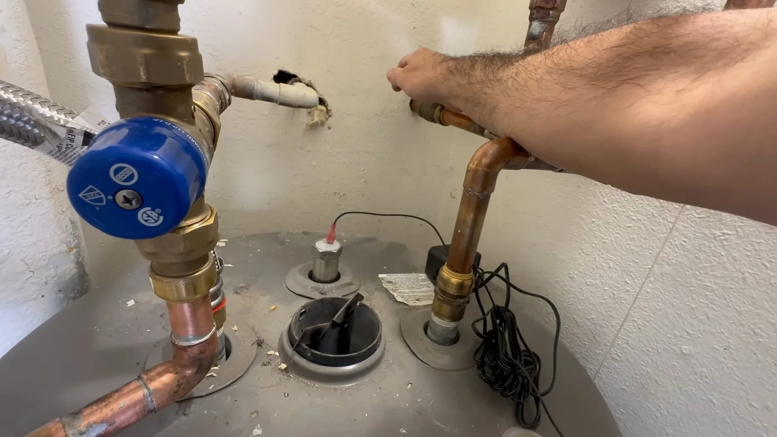 Top of a tank water heater with a blue valve, copper piping and a relief fitting