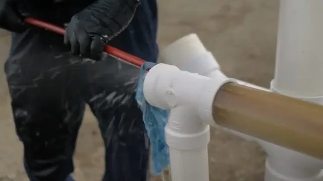 Worker pushing a jetting hose into a PVC tee while water sprays back out